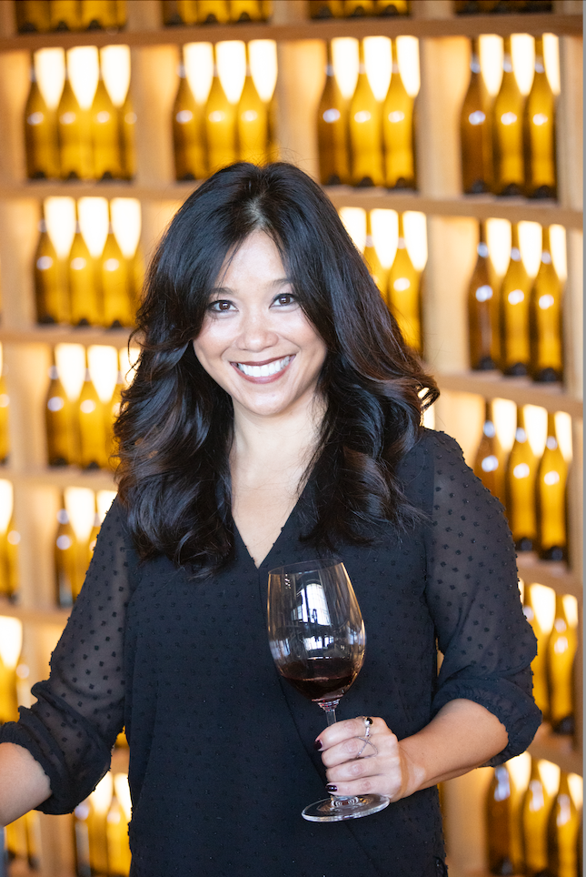 Bonnary Lek smiling in a black top holding a glass of wine