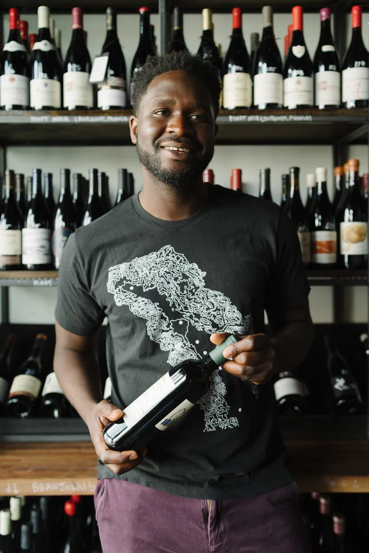 Femi Oyediran holding a bottle of wine, smiling