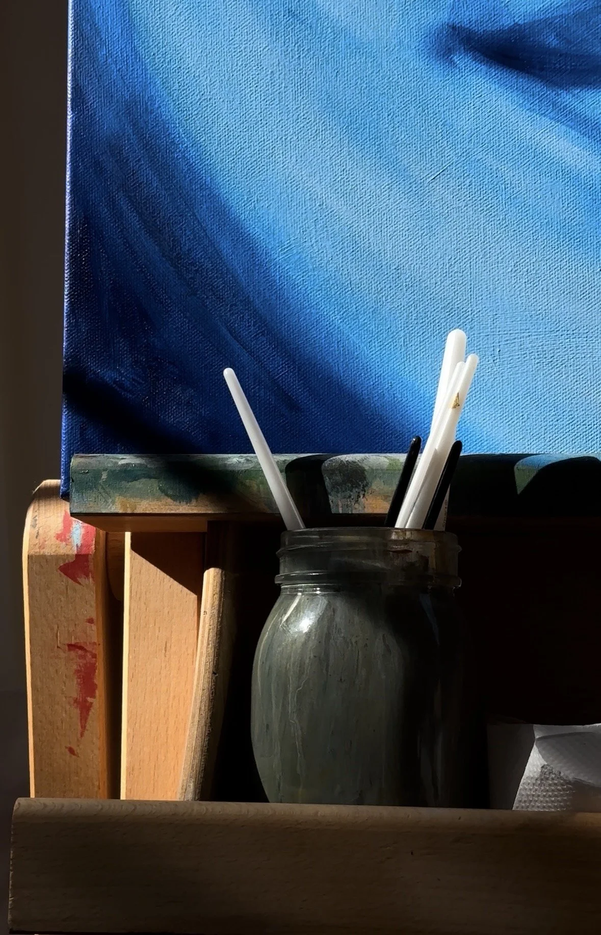 Oil painting and jar of paint brushes