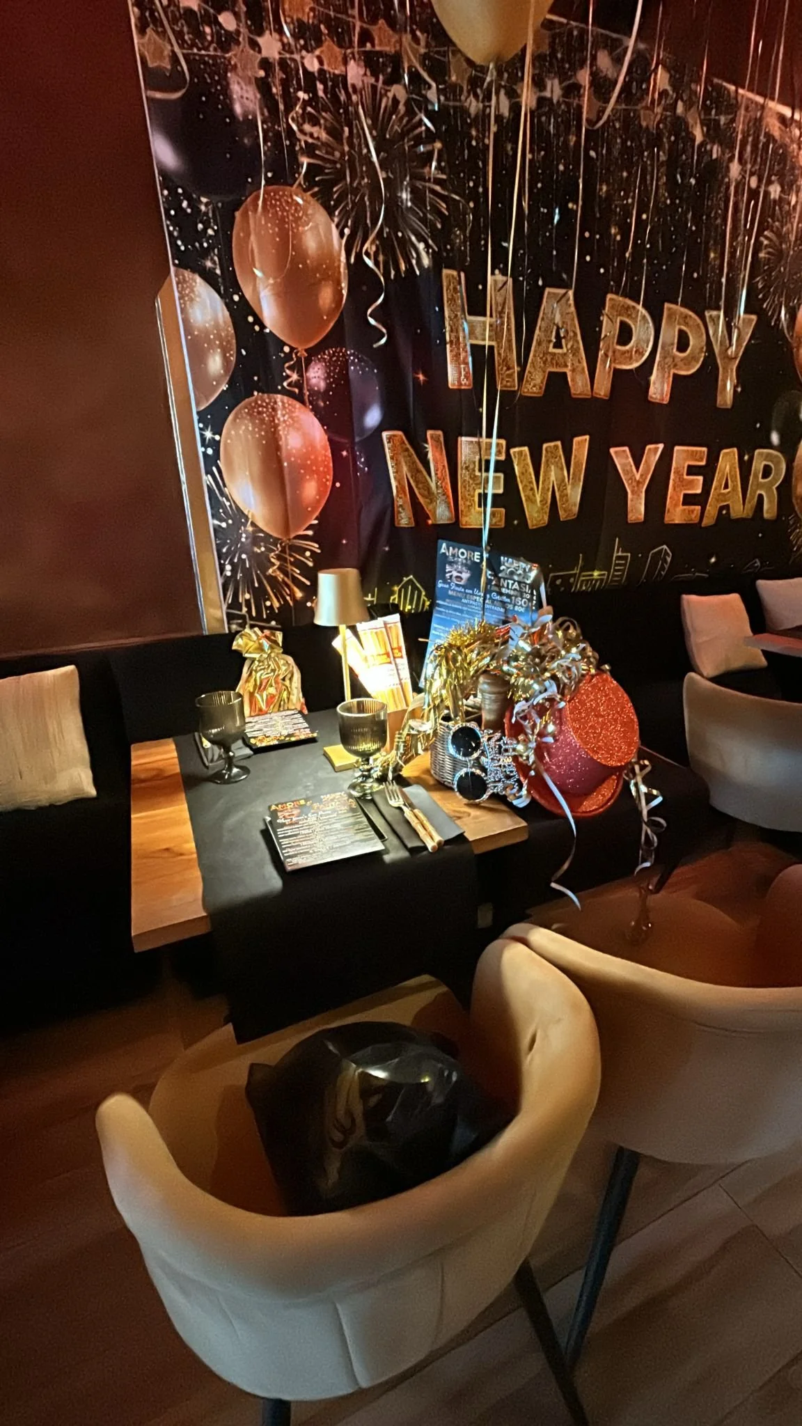 Decoración de celebración de Año Nuevo con globos dorados, serpentinas y un cartel que dice 'Feliz Año Nuevo'.