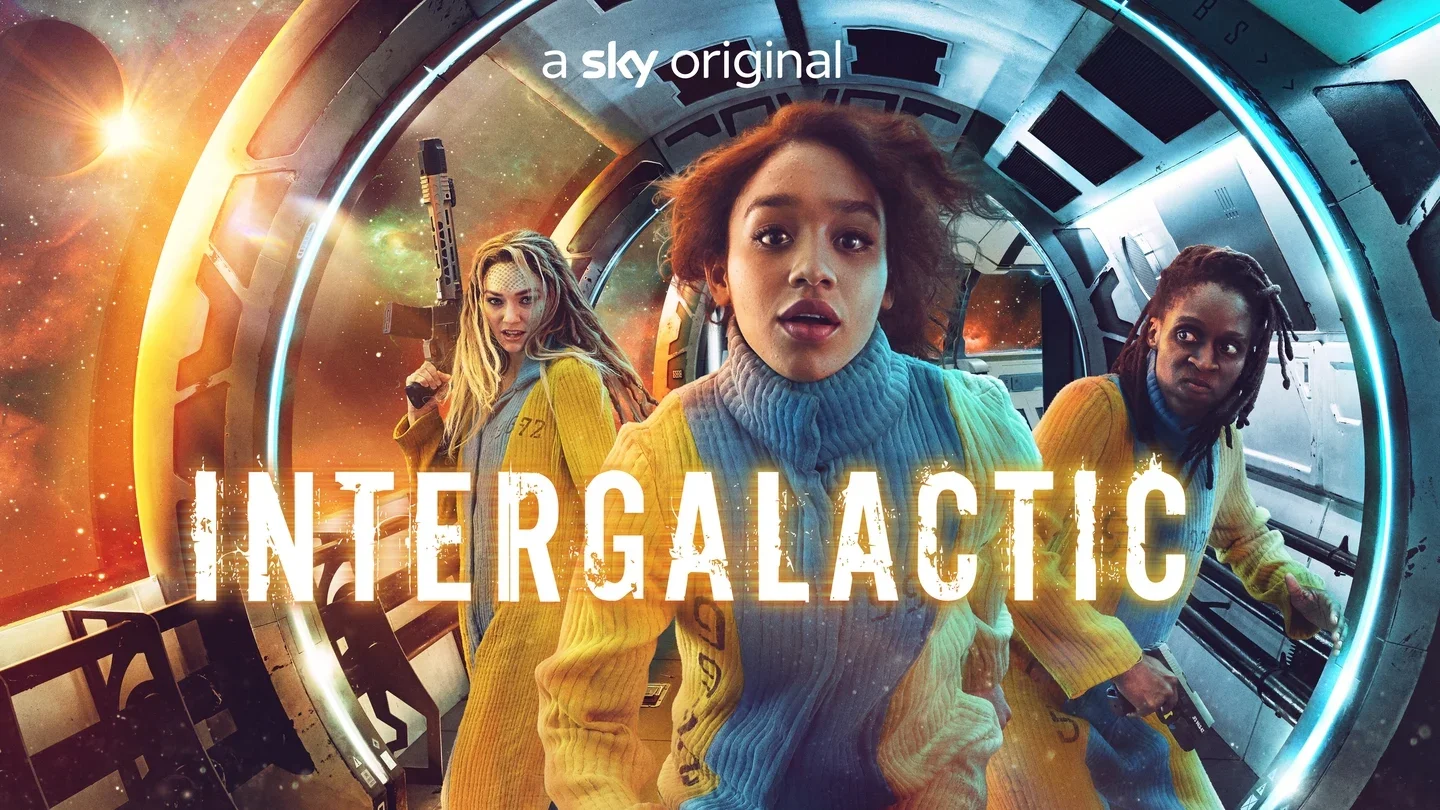 Three women in yellow space suits walk through a futuristic spaceship corridor with a space scene outside the window, and the title 'Intergalactic' overlays the image.
