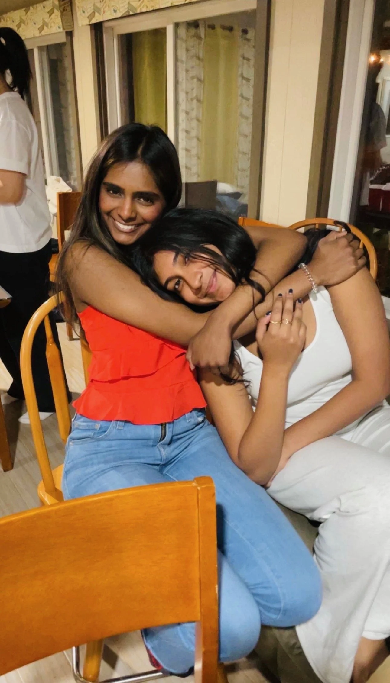 Two women hugging and smiling at a restaurant or cafe.