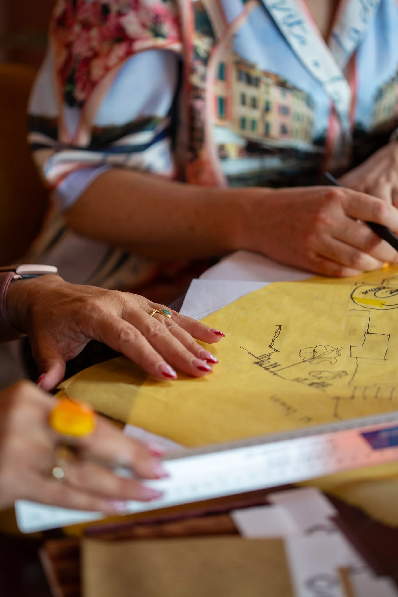 Liife Architecture team working on hospitality venue floor plans in their Ashgrove studio — two sets of hands sketching on trace paper with a scale ruler.