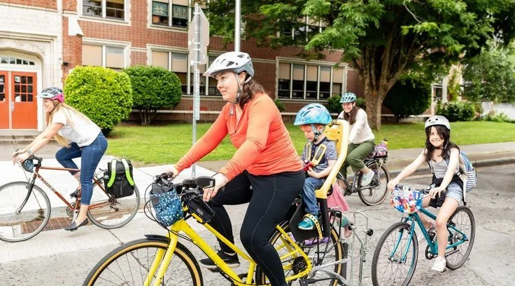 adults with children riding bikes to school