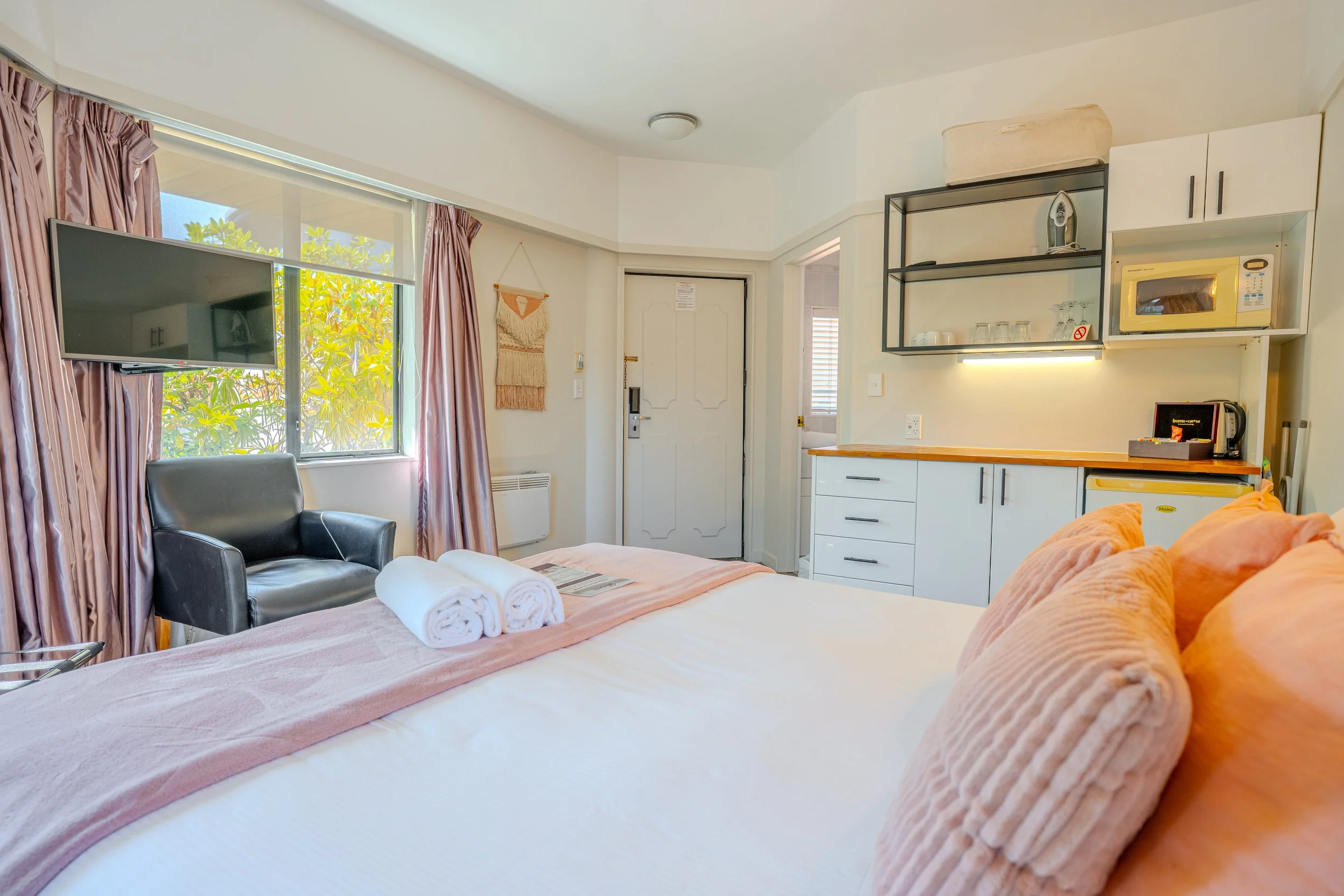 Studio accommodation featuring a queen bed, kitchenette, seating area, and modern amenities.