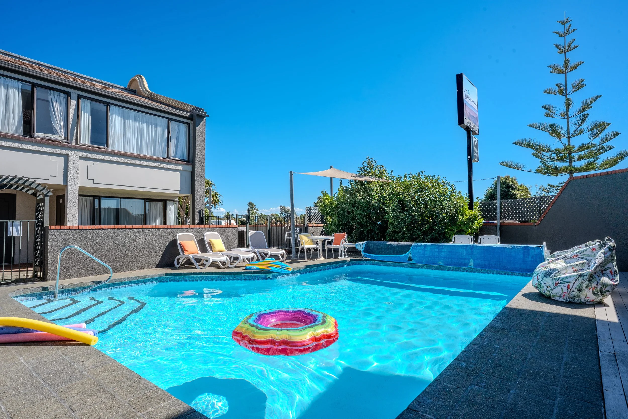 Outdoor swimming pool with sun loungers, poolside seating, and relaxation area.