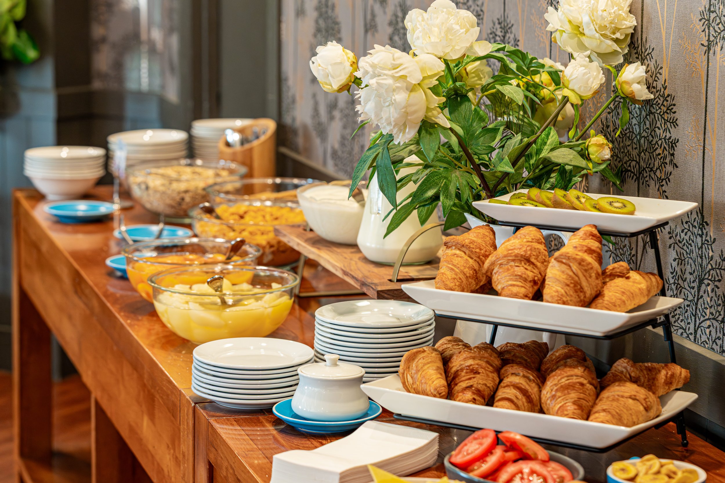 Continental breakfast buffet with fresh pastries, fruit, cereals, and hot beverages.