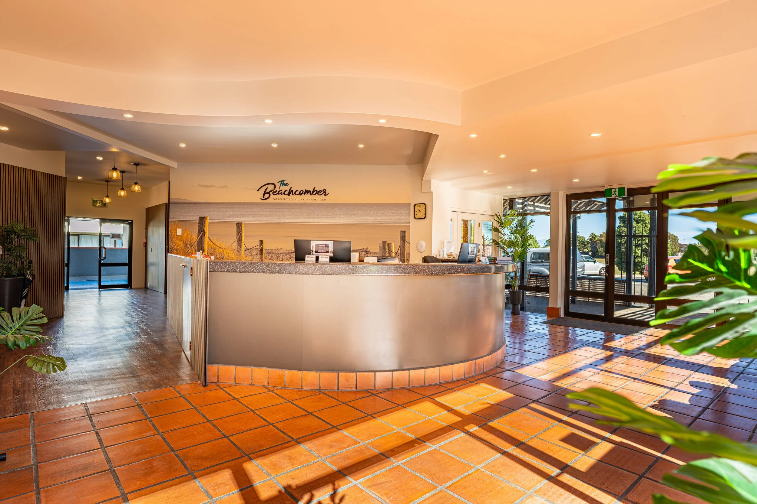 Reception area at Beachcomber Hotel featuring a welcoming front desk, tiled flooring, and bright natural light.