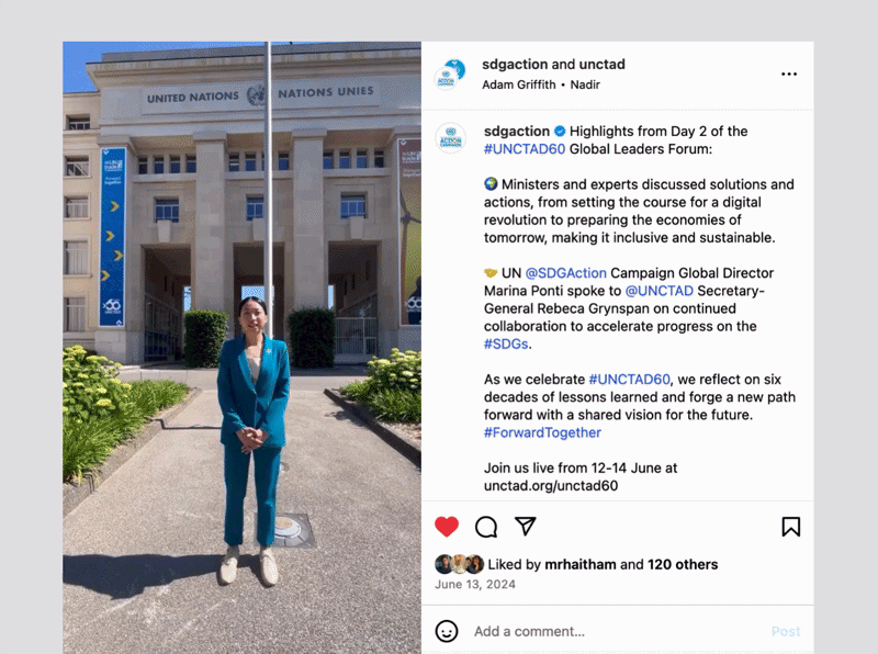 Woman in blue suit standing in front of United Nations building with banners on the side during the day.