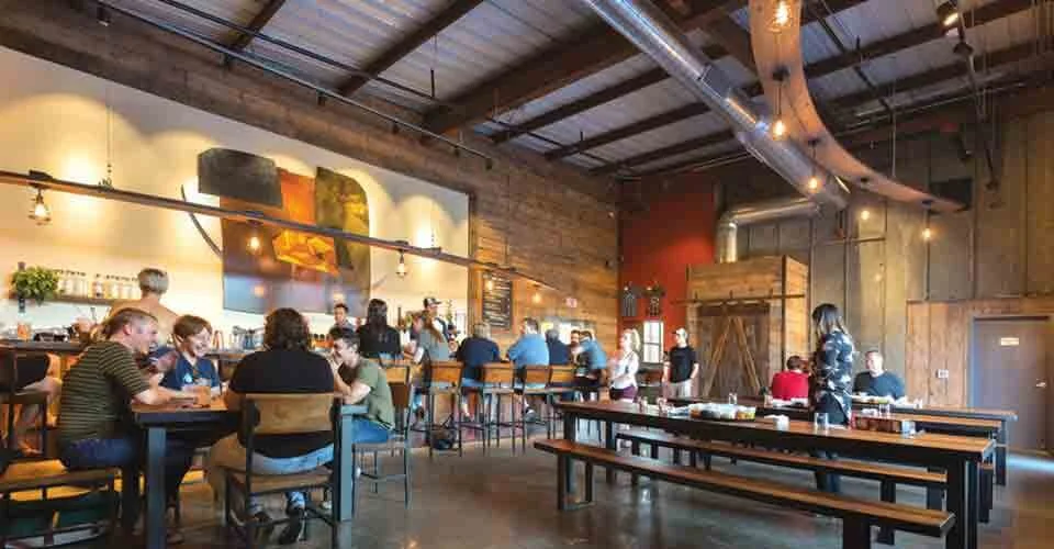Stateline Distillery's tasting room with industrial design to create an inviting space with metal, wood, copper, and concrete surfaces.