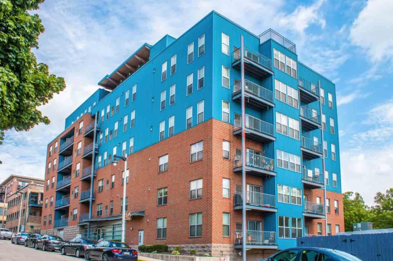 Seven story apartment building with red brick on the first three floors. Then blue siding lining the rest of the building.
