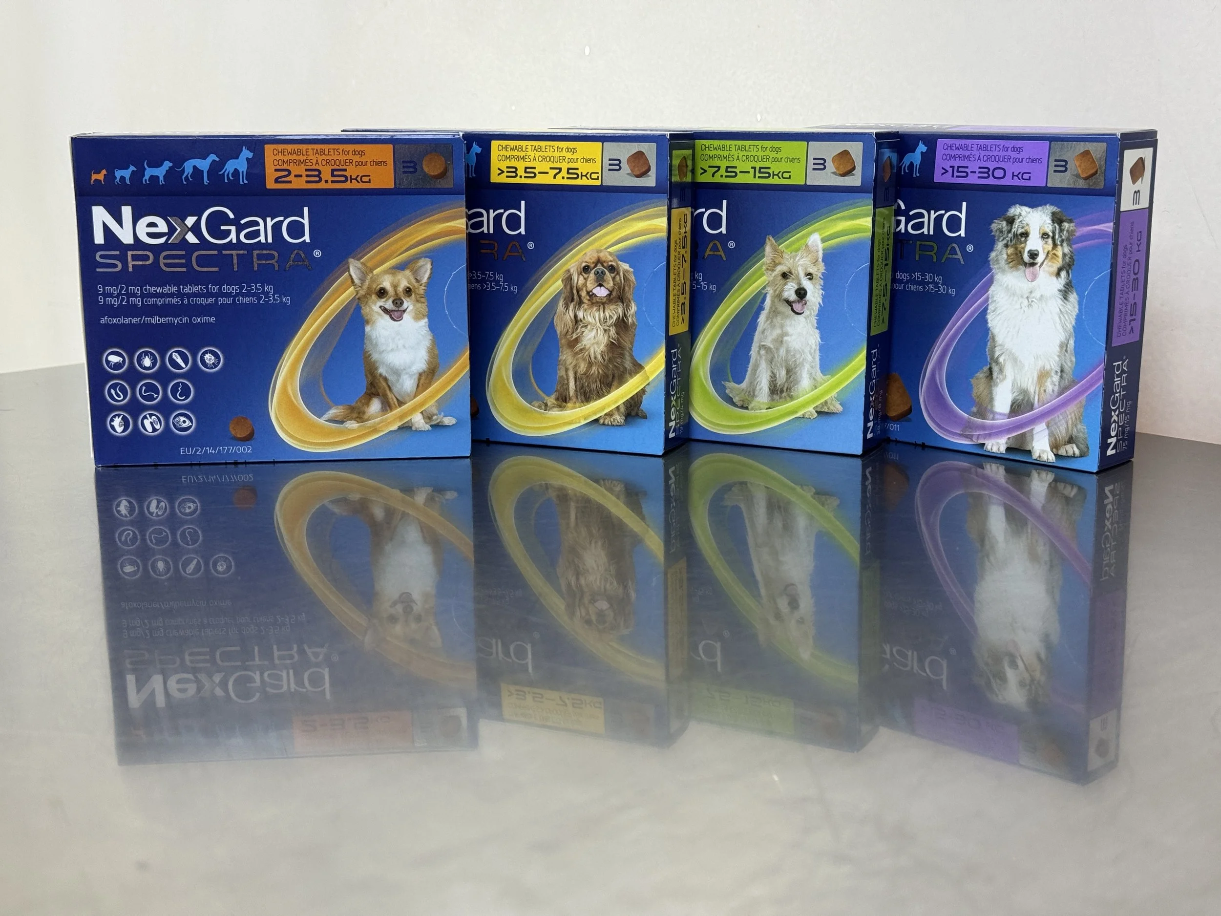 Four boxes of NexGard Spectra dog medication arranged in a row. Each box features an image of a different dog breed, with color-coded labels indicating suitable dog weight ranges from 2-3.5 kg, 3.5-7.5 kg, 7.5-15 kg, and 15-30 kg.
