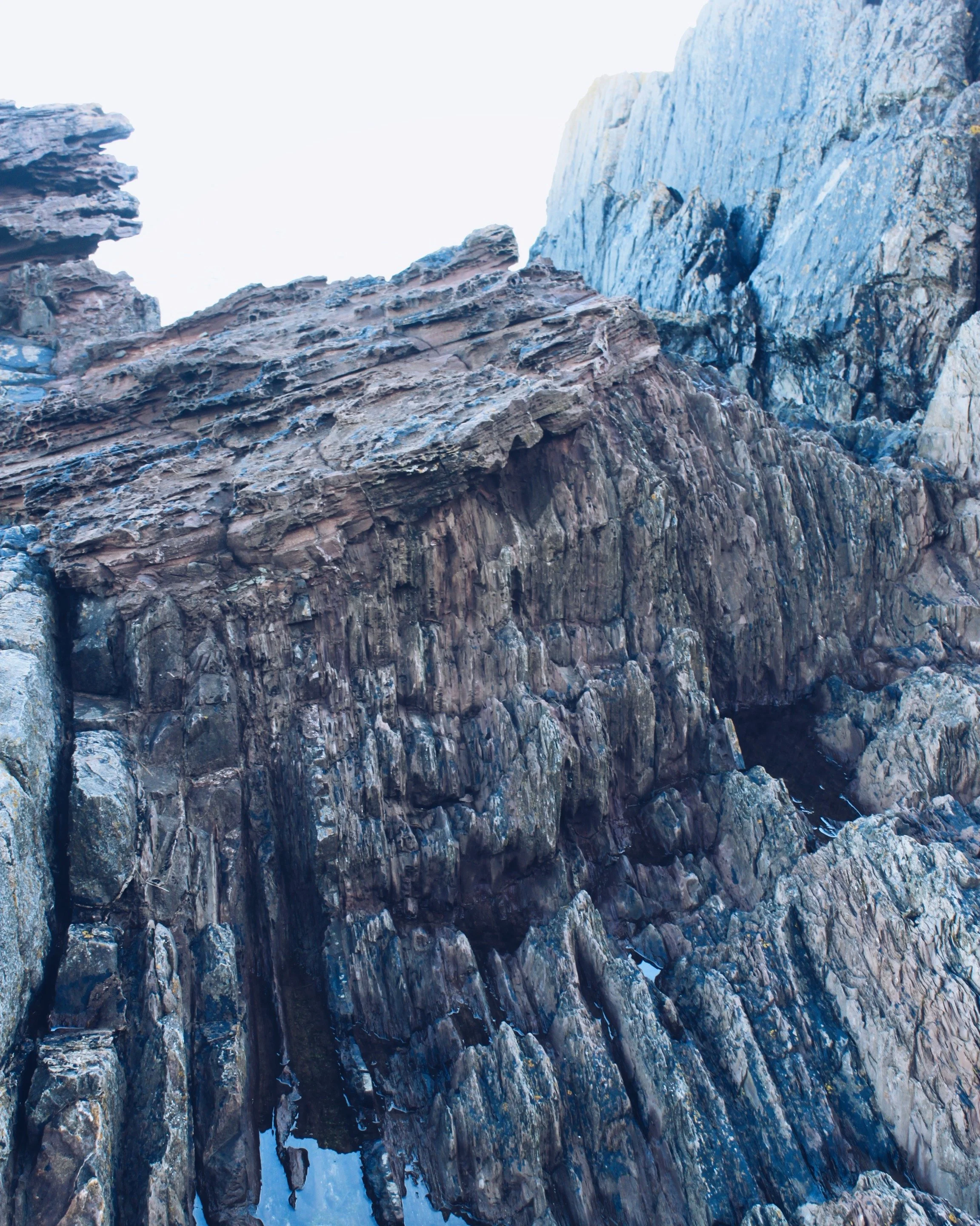 Layers of rock point vertically with layers of horizontal facing rocks on top