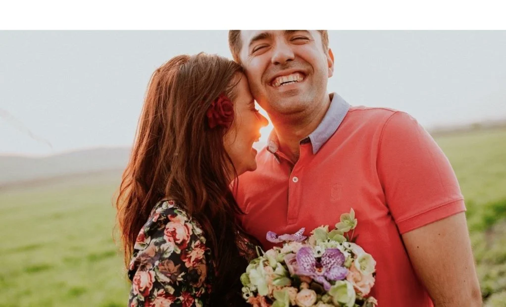 A smiling couple holding flowers