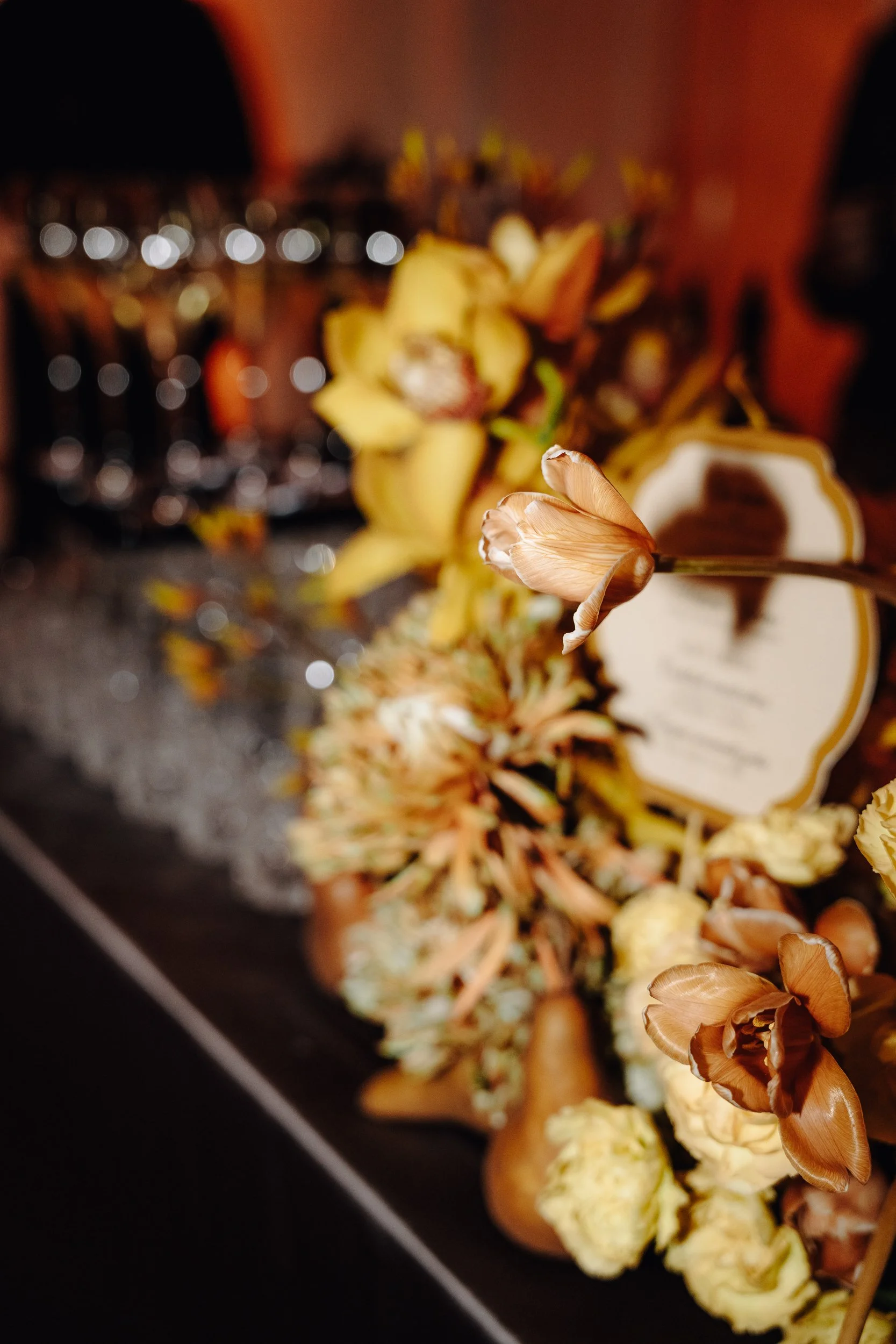 Close-up of dried flowers and a decorative object on a black surface, with blurred background.