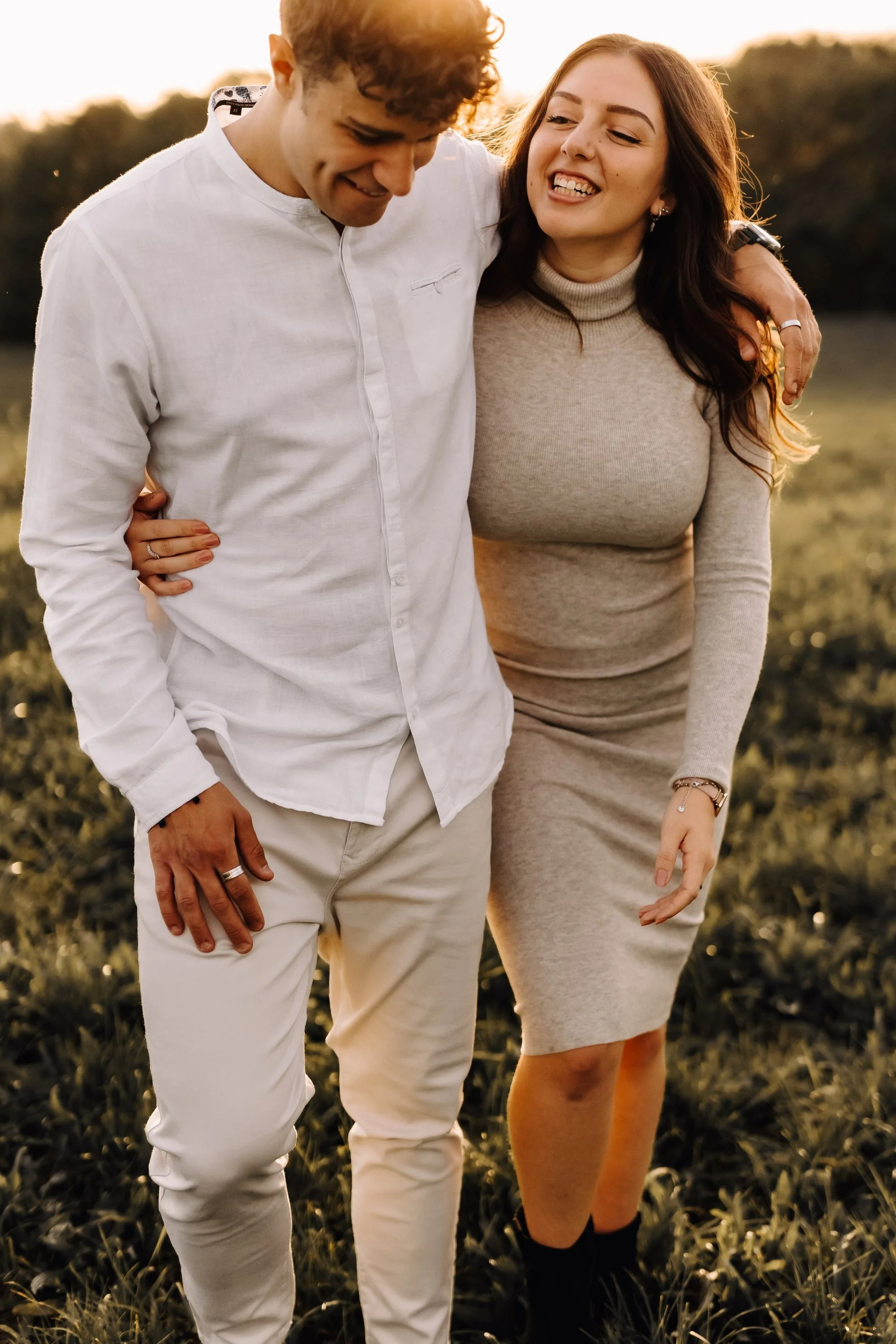 A young man and woman walking together outdoors during sunset, smiling and enjoying each other's company.