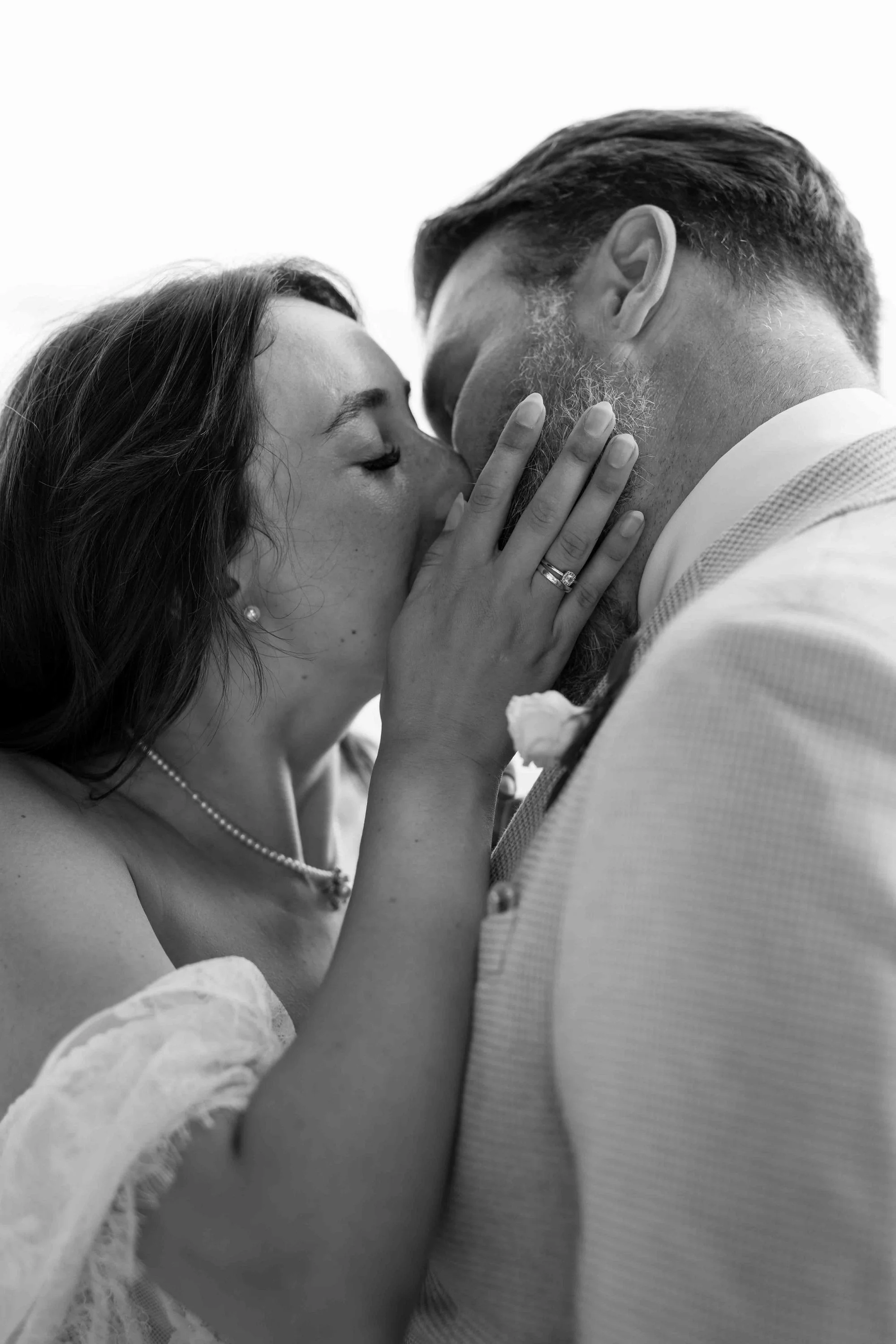 A woman and man sharing a kiss, with the woman gently touching the man's face.
