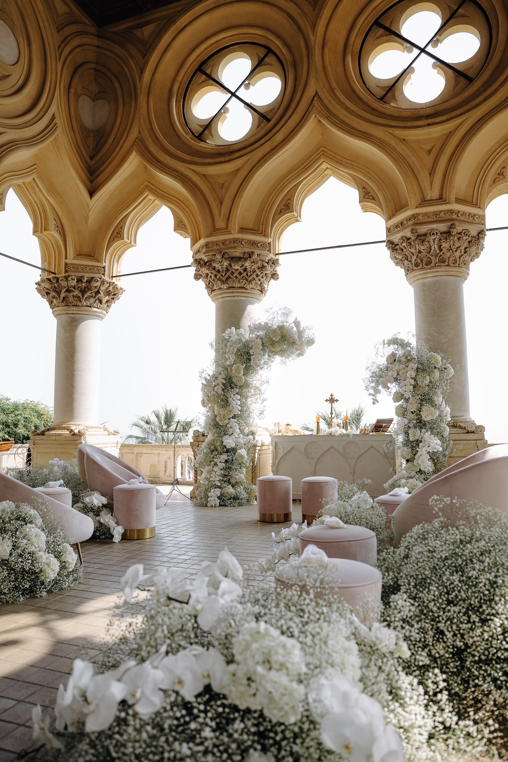 Elegant wedding altar with floral arrangements, columns, and draped ceiling in a historic building.