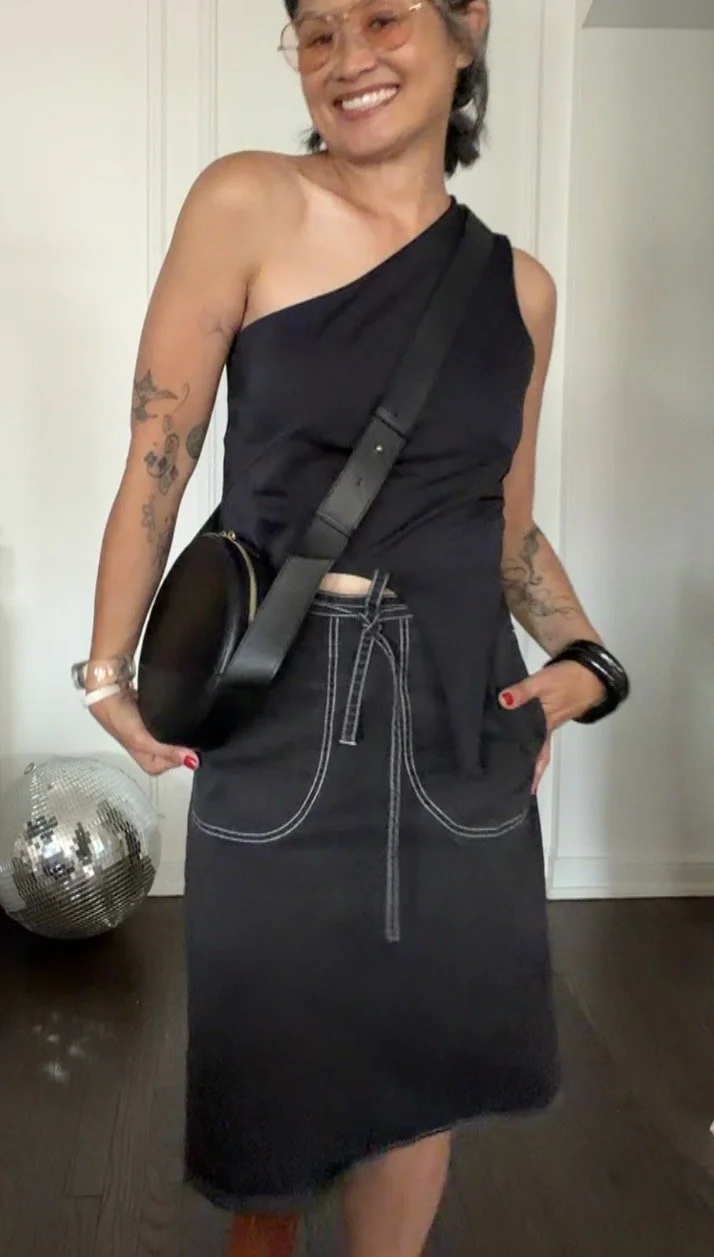 Woman wearing a modern black one-shoulder top with a vintage-inspired black skirt.