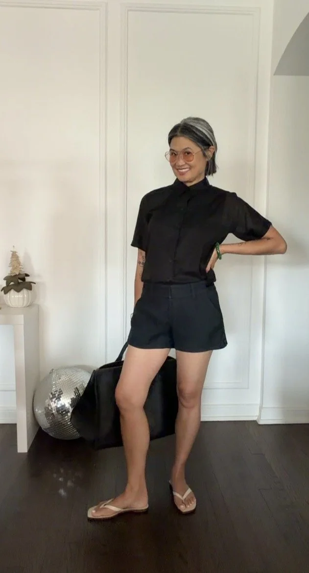 Menswear-inspired black summer outfit for women featuring a camp shirt and shorts.