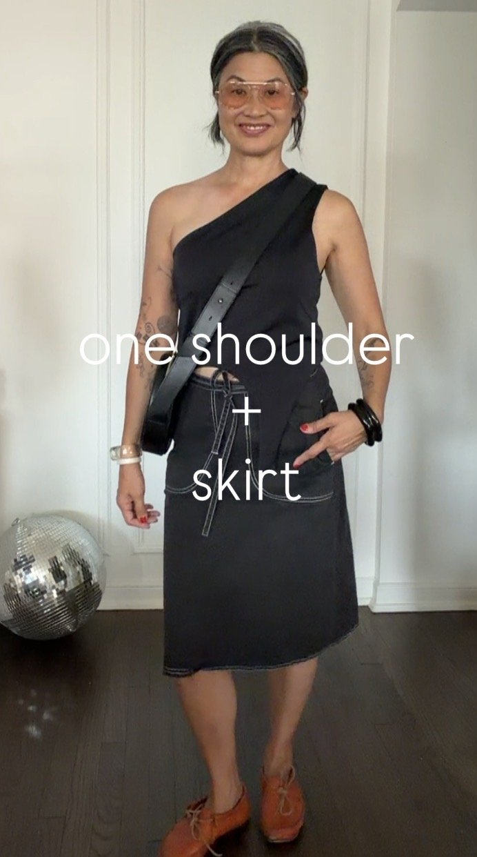Woman wearing a modern black one-shoulder top with a vintage-inspired black skirt.