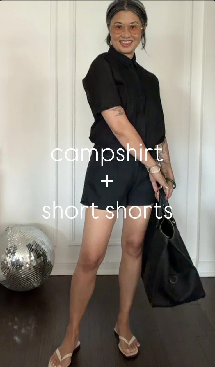 Black camp shirt buttoned to the top paired with black short shorts for a menswear-inspired summer outfit.