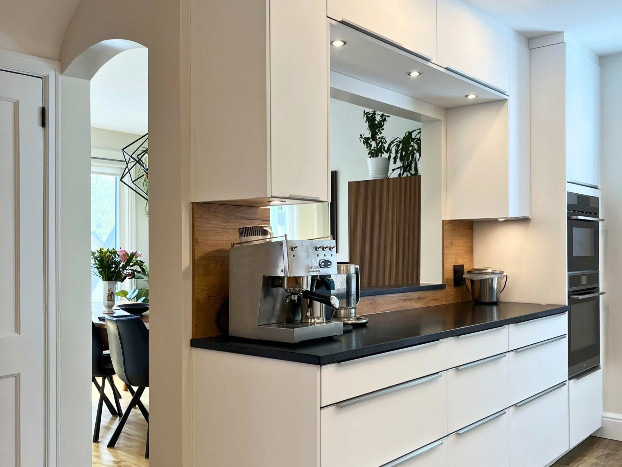 Custom white kitchen cabinets with integrated lighting and handleless drawers.
