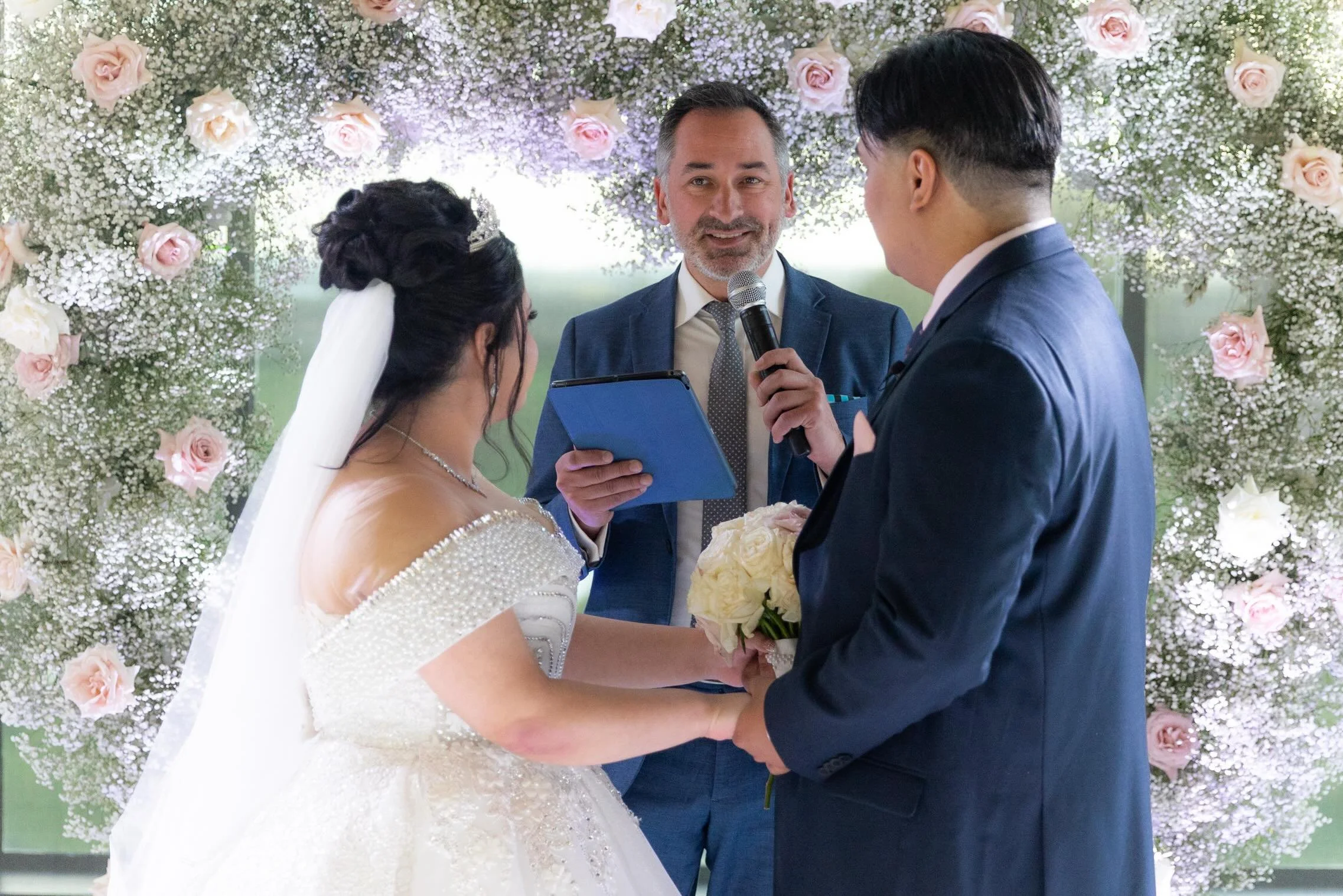 Pure elegance from start to finish. 🌸🤍

Kris had the joy of officiating this absolutely breathtaking ceremony for F &amp; L, framed by a floor-to-ceiling arch of blush roses and baby&rsquo;s breath, with floor-length windows pouring in light and a 