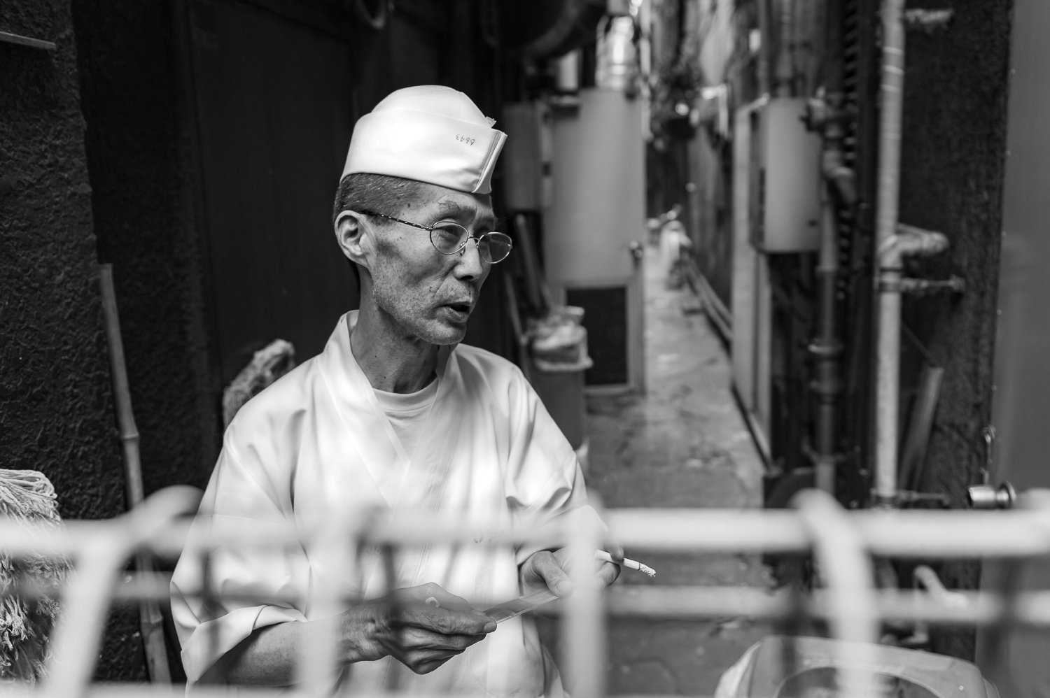A cook smoking a cigarette in the Ueno Market back alley. Ueno is Tokyo's best location for street photography.