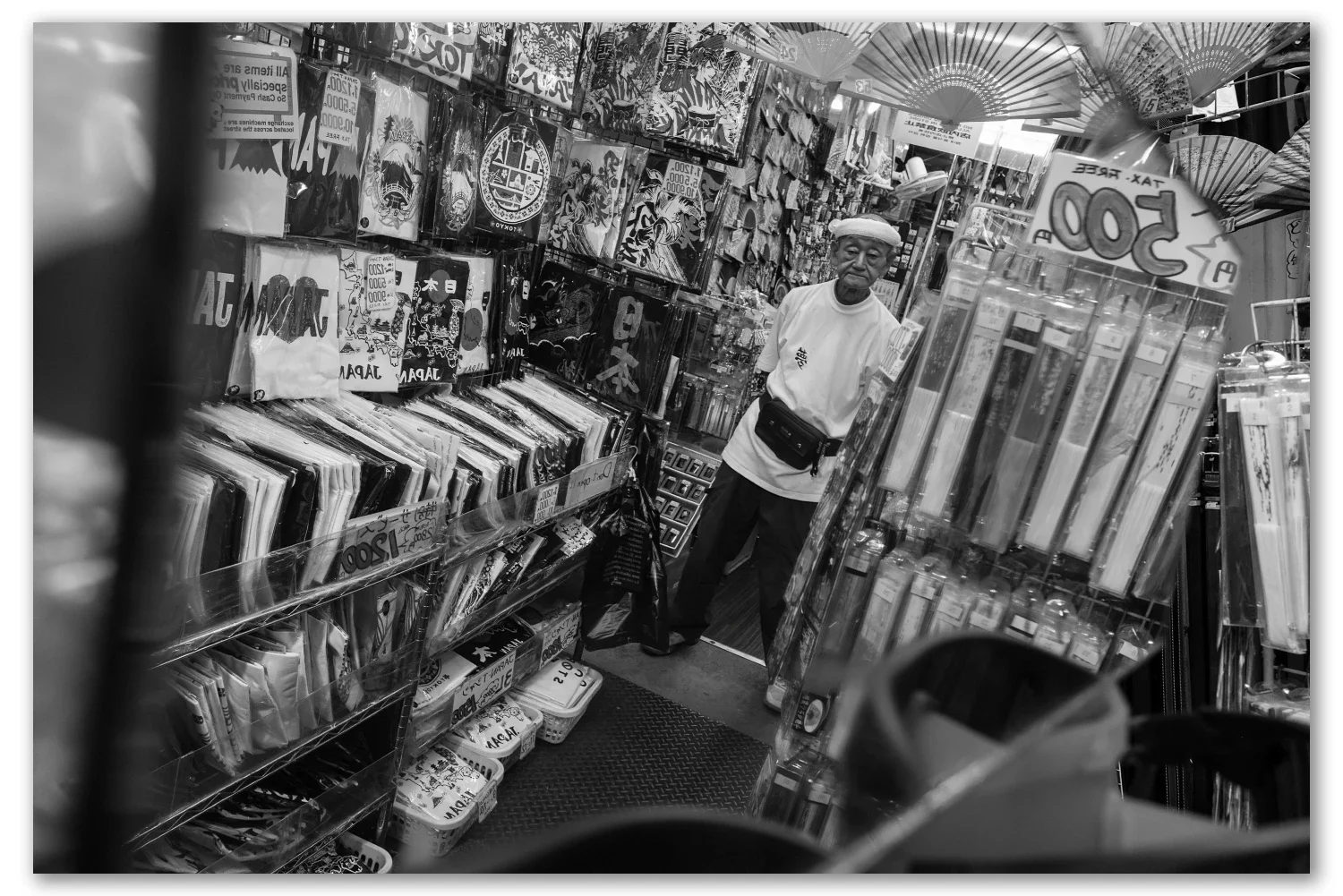 A shopkeeper in a white cap among racks of stock at a crowded stall in Ameyoko, Ueno]