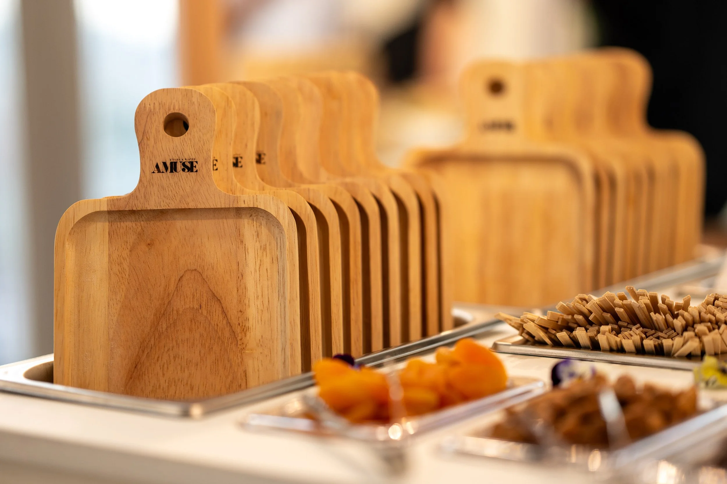 Stacked wooden cutting boards and serving trays with desserts and snacks on a table.