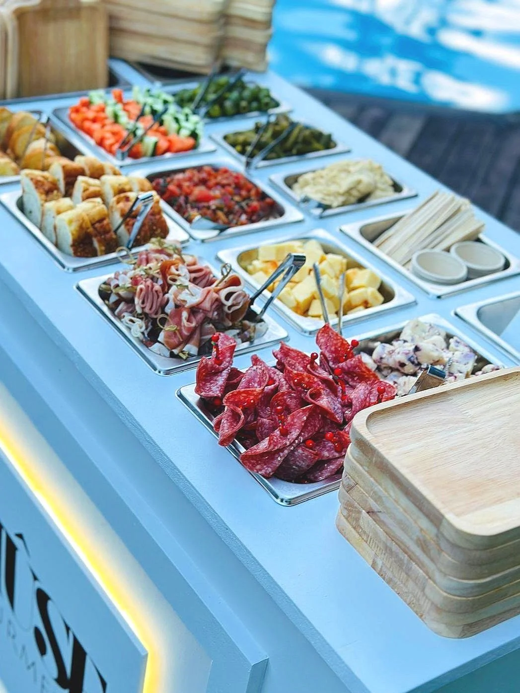 Buffet with various sliced vegetables, cheeses, meats, dips, bread, and condiments displayed on a white table.
