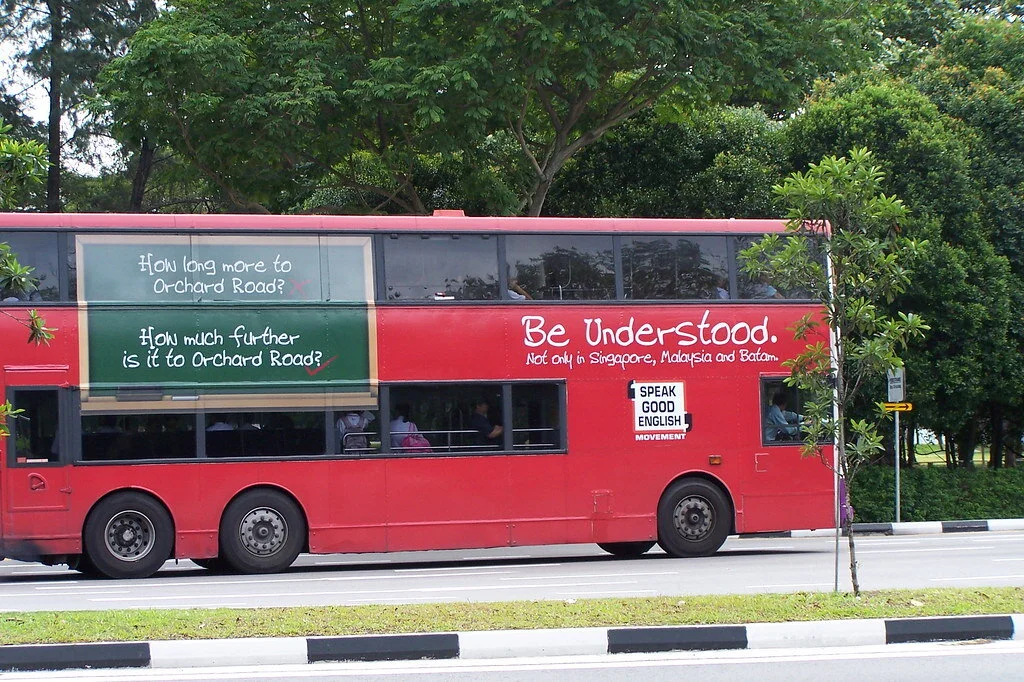 Red bus with 'speak good English' advertisement on it.