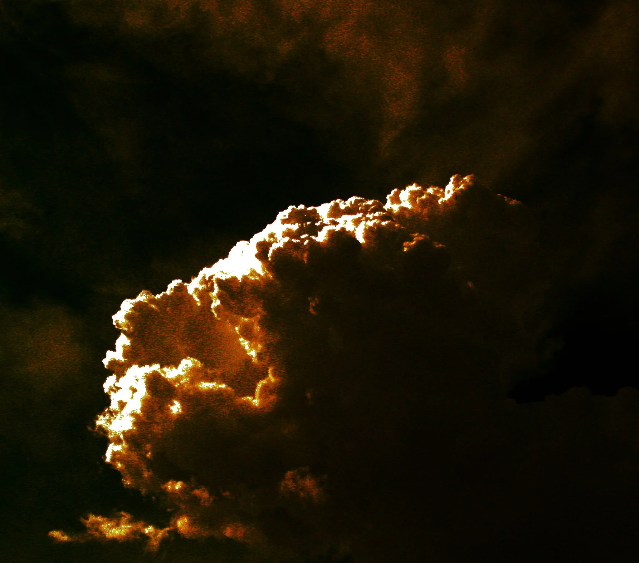 A cloud burst created by an explosion at night. The cloud is illuminated by the fire caused by the explosion, turning it orange.