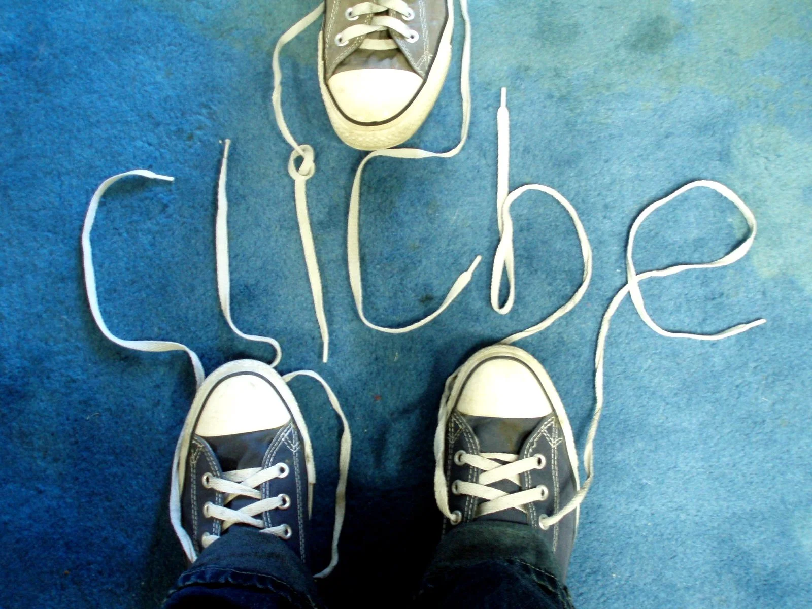 The word cliche is written out using the shoelaces of a pair of blue Converse sneakers.