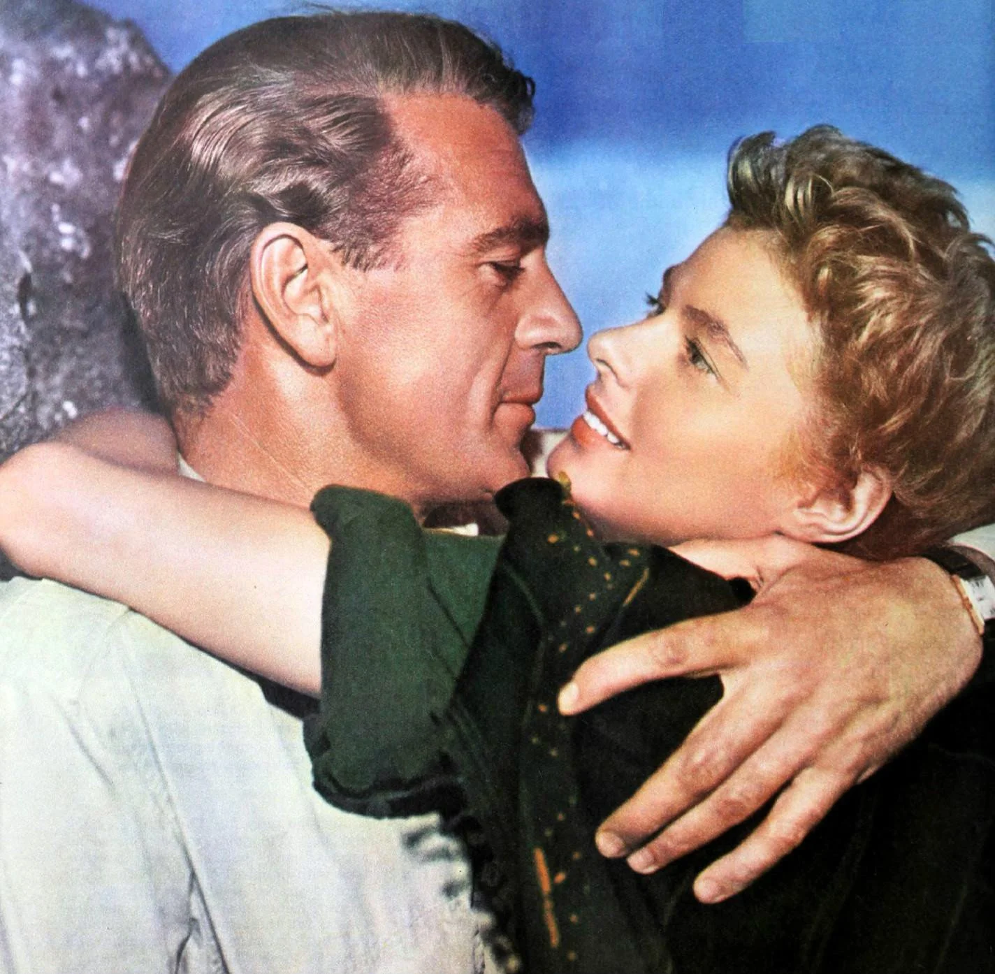 Actors Gary Cooper and Ingrid Bergman pose in a hug, smiling into each other's eyes, in a poster advertising the film, For Whom the Bell Tolls.