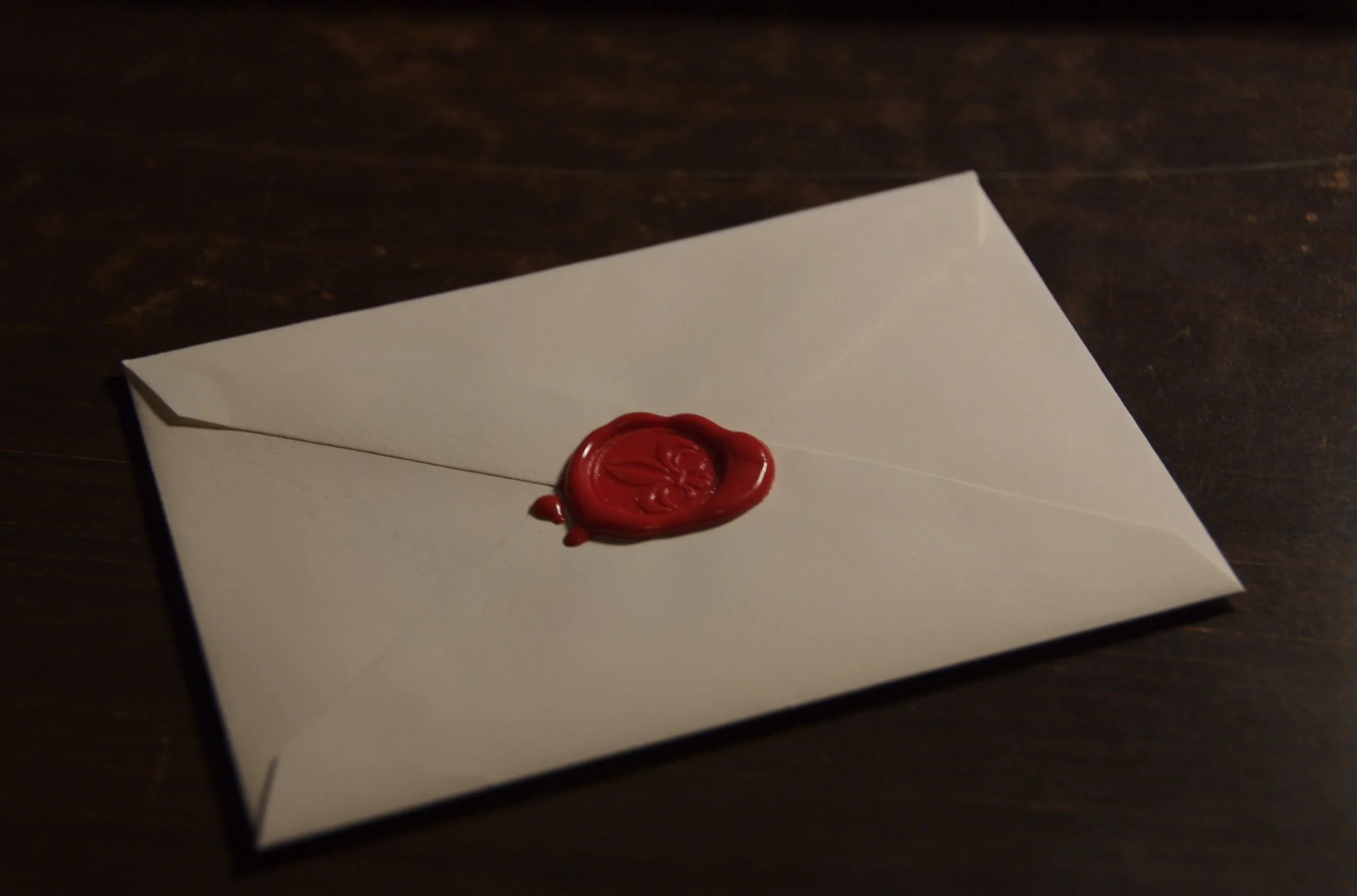 A red wax stamp seals a white envelope.