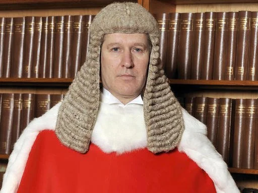 A judge from the UK, Justice Peter Jackson, wearing his judicial wig and robe.