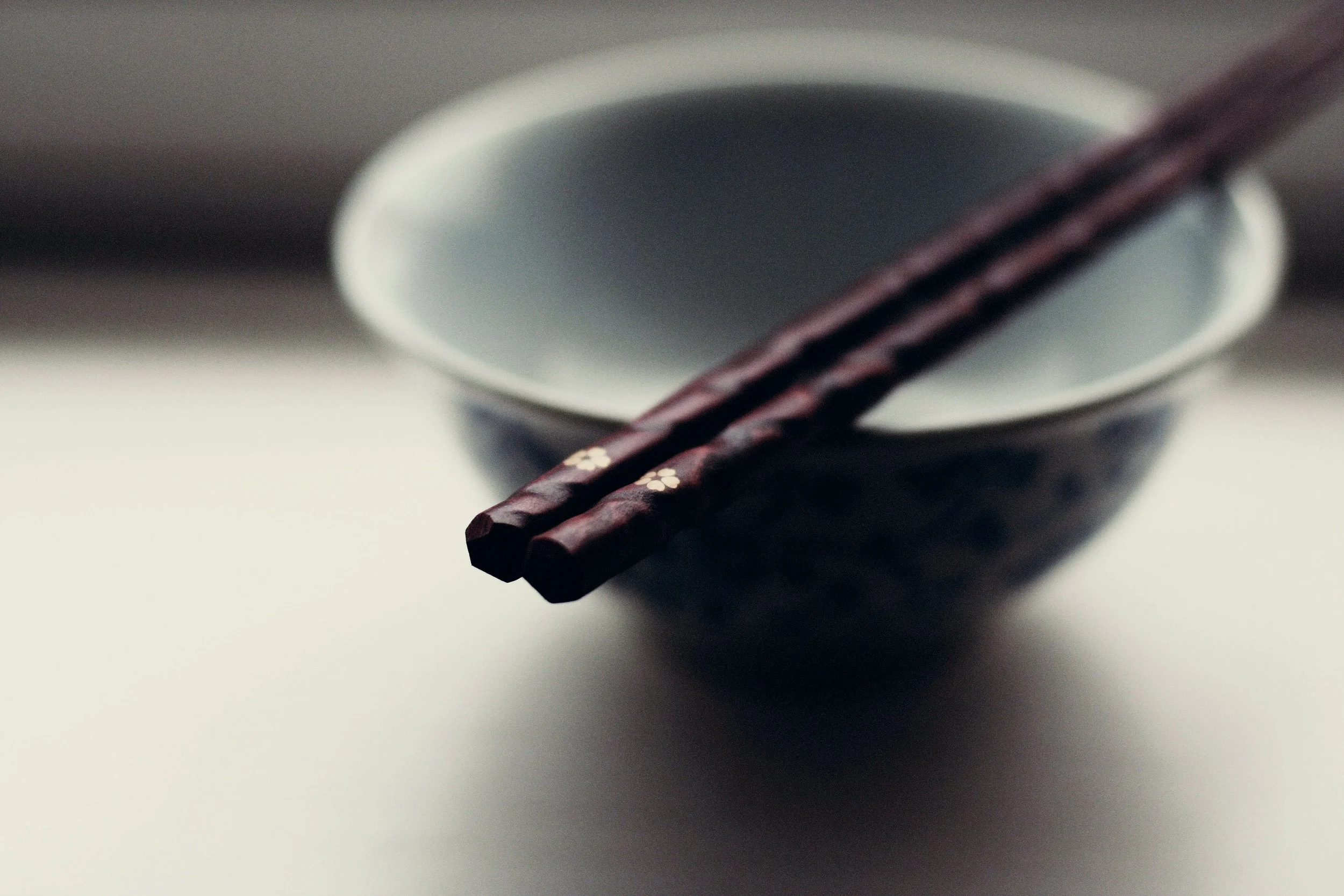 Wooden chopsticks rest on top of an empty white bowl.