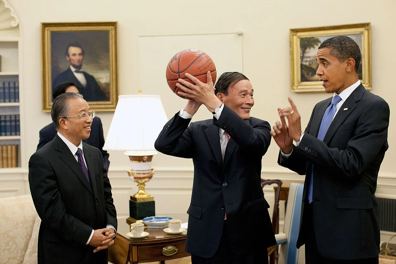 Chinese Vice Premier Wang Qishan holds an autographed basketball, a gift by President Barack Obama, standing beside him, after a meeting at the Oval Office, July 2009.