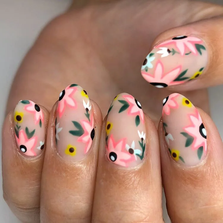 Close-up of a hand with floral nail art on nails, featuring pink, white, yellow, black, and green colors in a floral pattern.