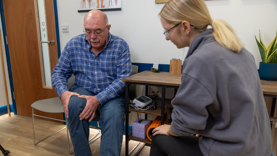 A man describes his knee pain to sports therapist Hannah Bolwell