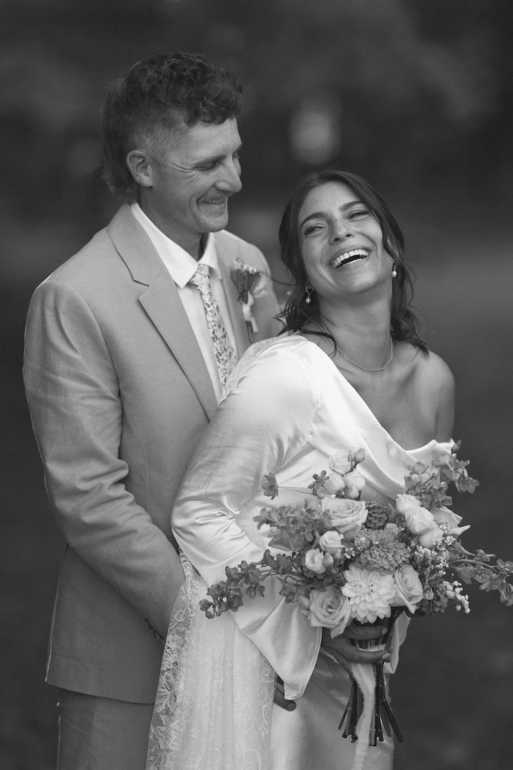Black and white photo of the groom smiling down at his bride.