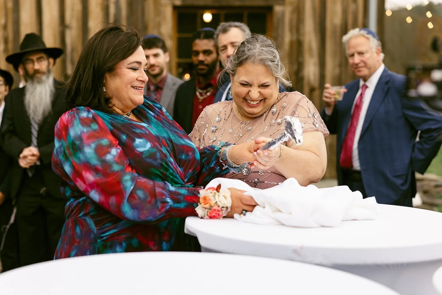The mom's of the wedding performing the traditional "breaking of the plate" with big smiles and laughs.