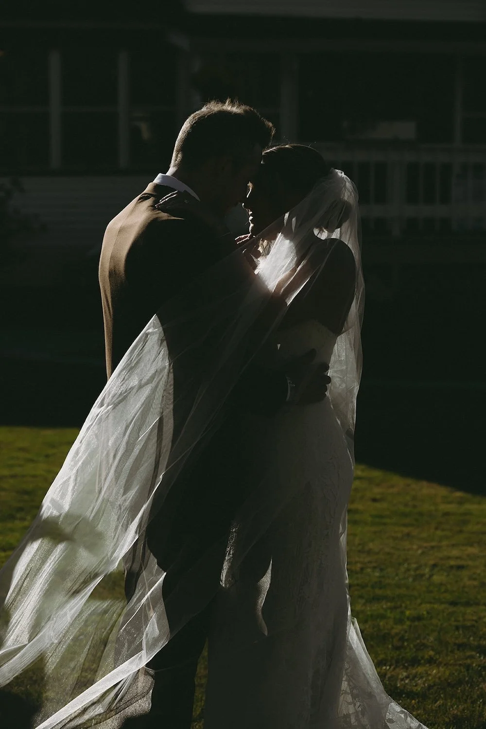 The bride and groom hold one another closely while the brides veil surrounds them.