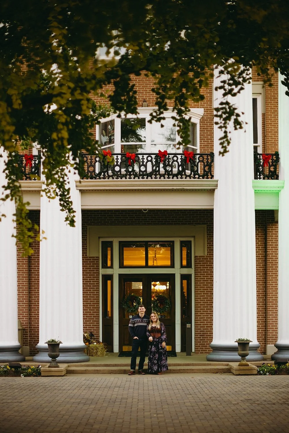 The couple standing at the historic courthouse building decorated in Christmas decorations.