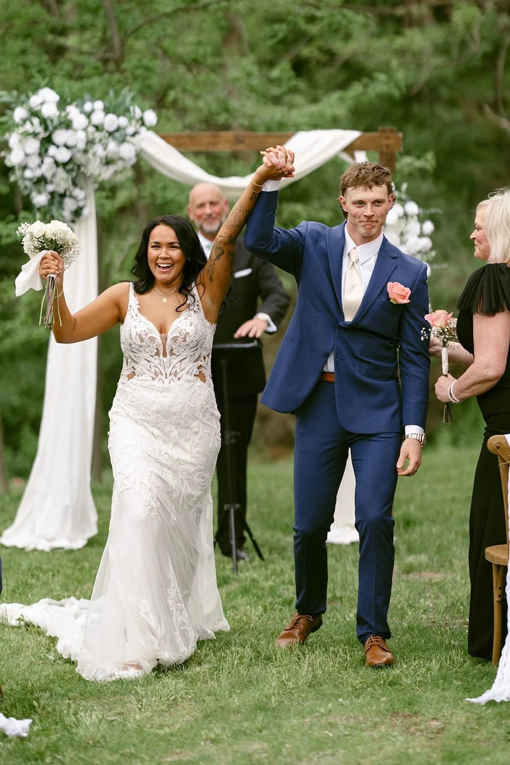 The bride and groom raise their hands in the air celebrating their new marriage.