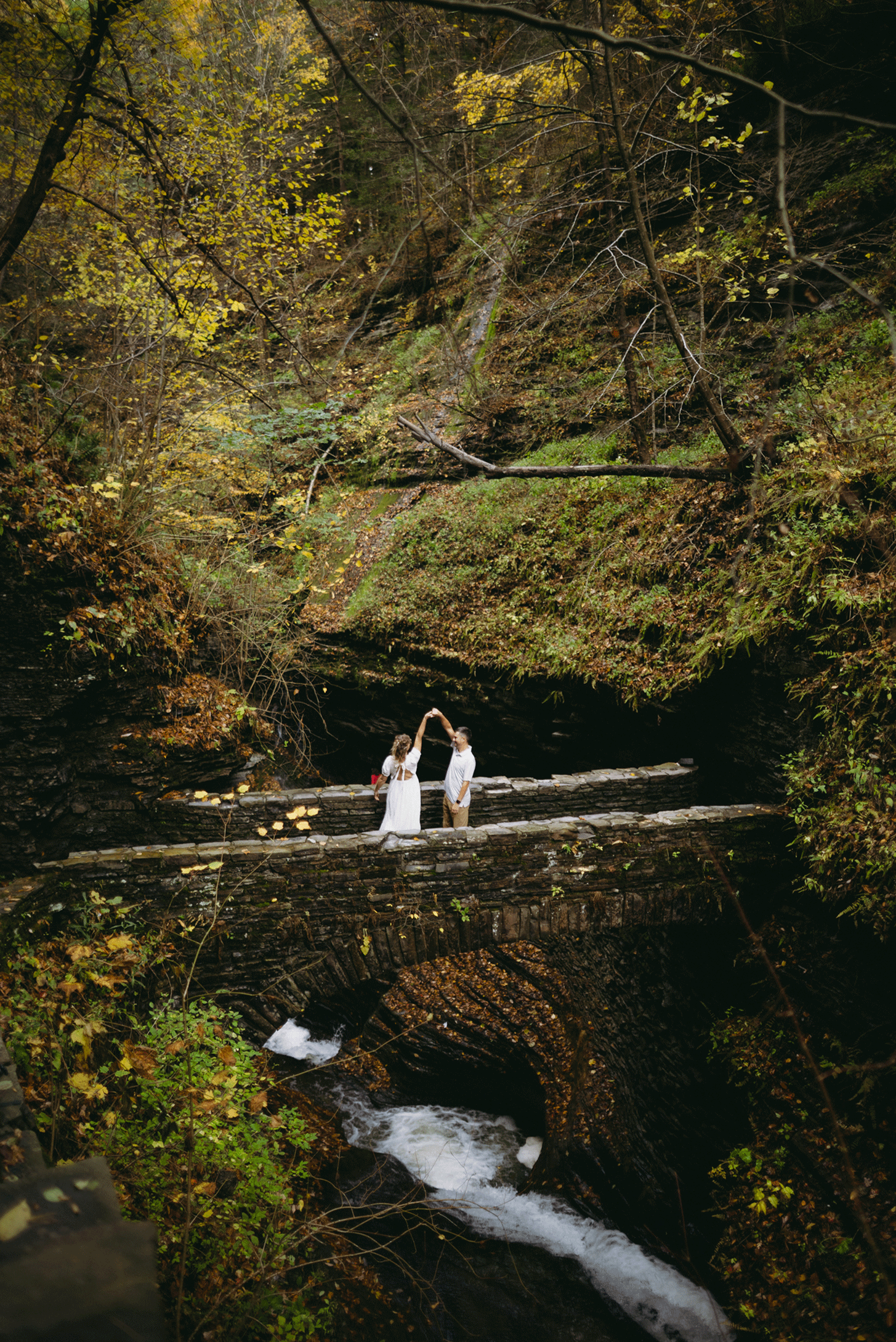 Live photo of the groom spining his bride in circles as they dance on the bridge.