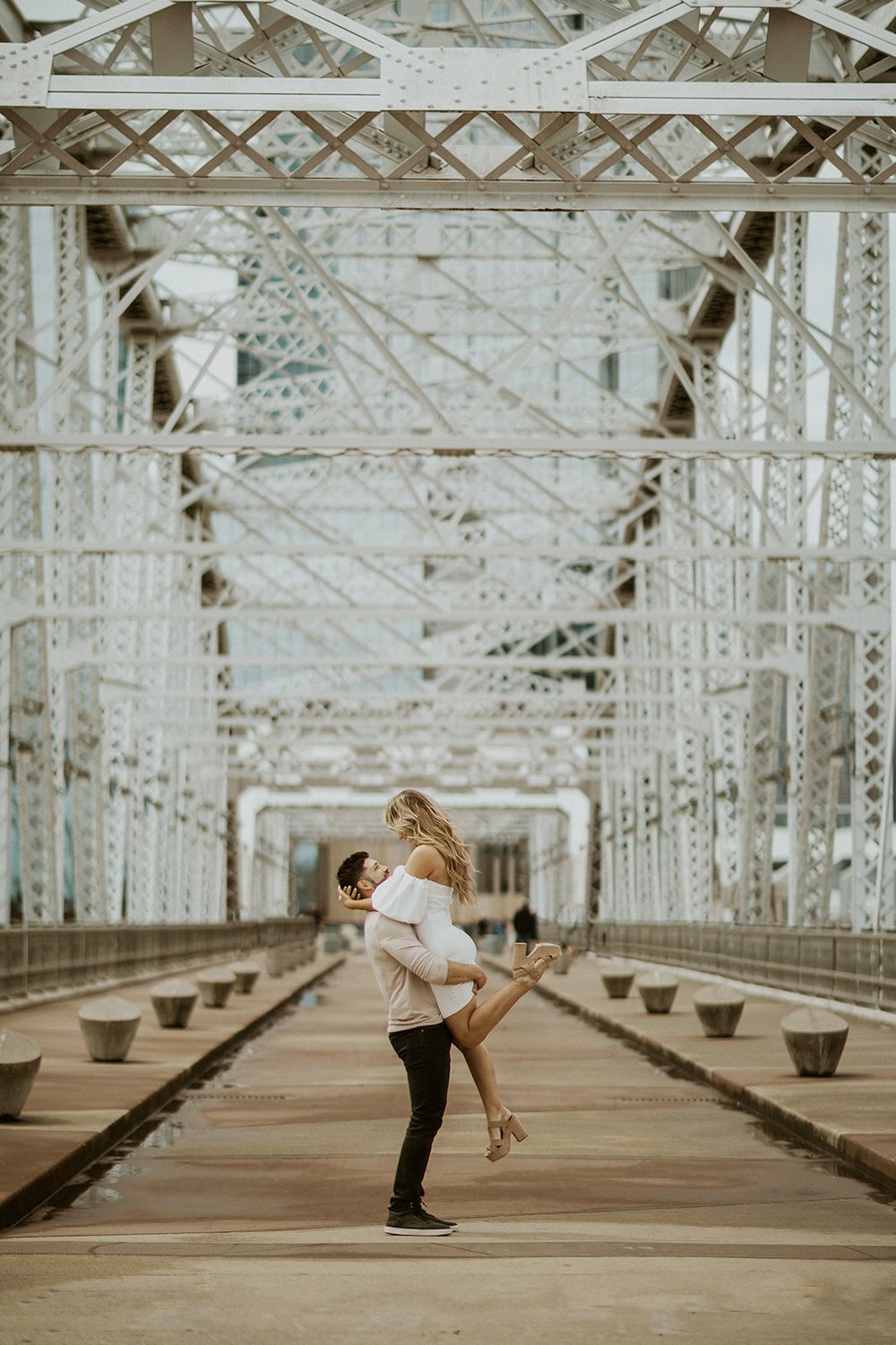 Husband lifts his wife with excitement while on the walking bridge from Downtown Nashville to the suburbs.