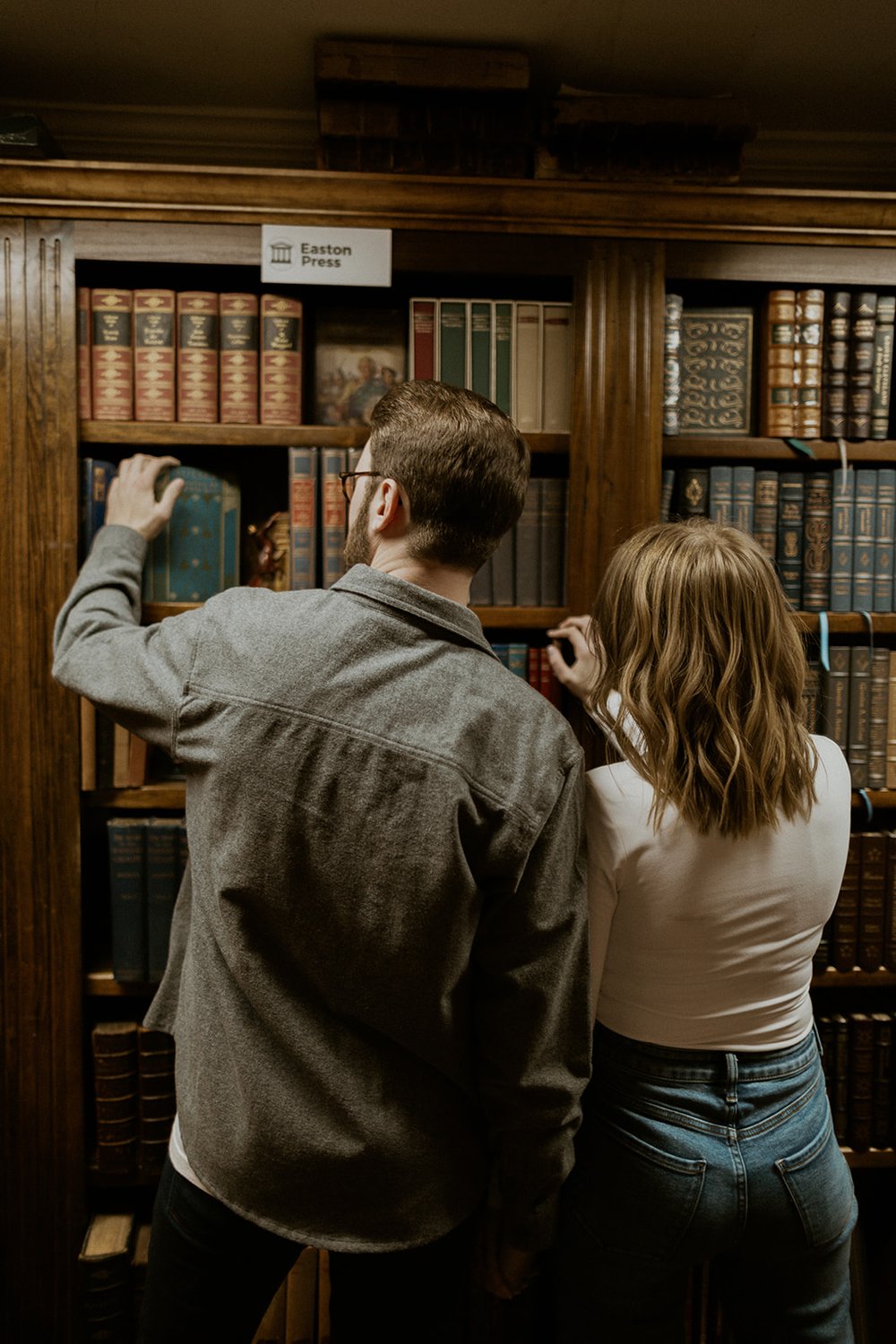 The couple search for a book to read together in their favorite book store.